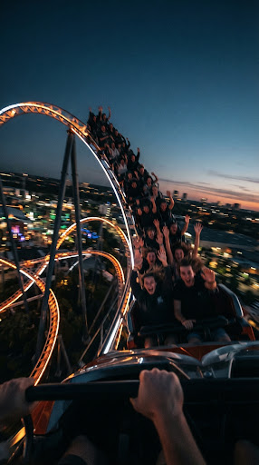 POV vertical still on a roller coaster at dusk with vibrant LED-lit tracks.